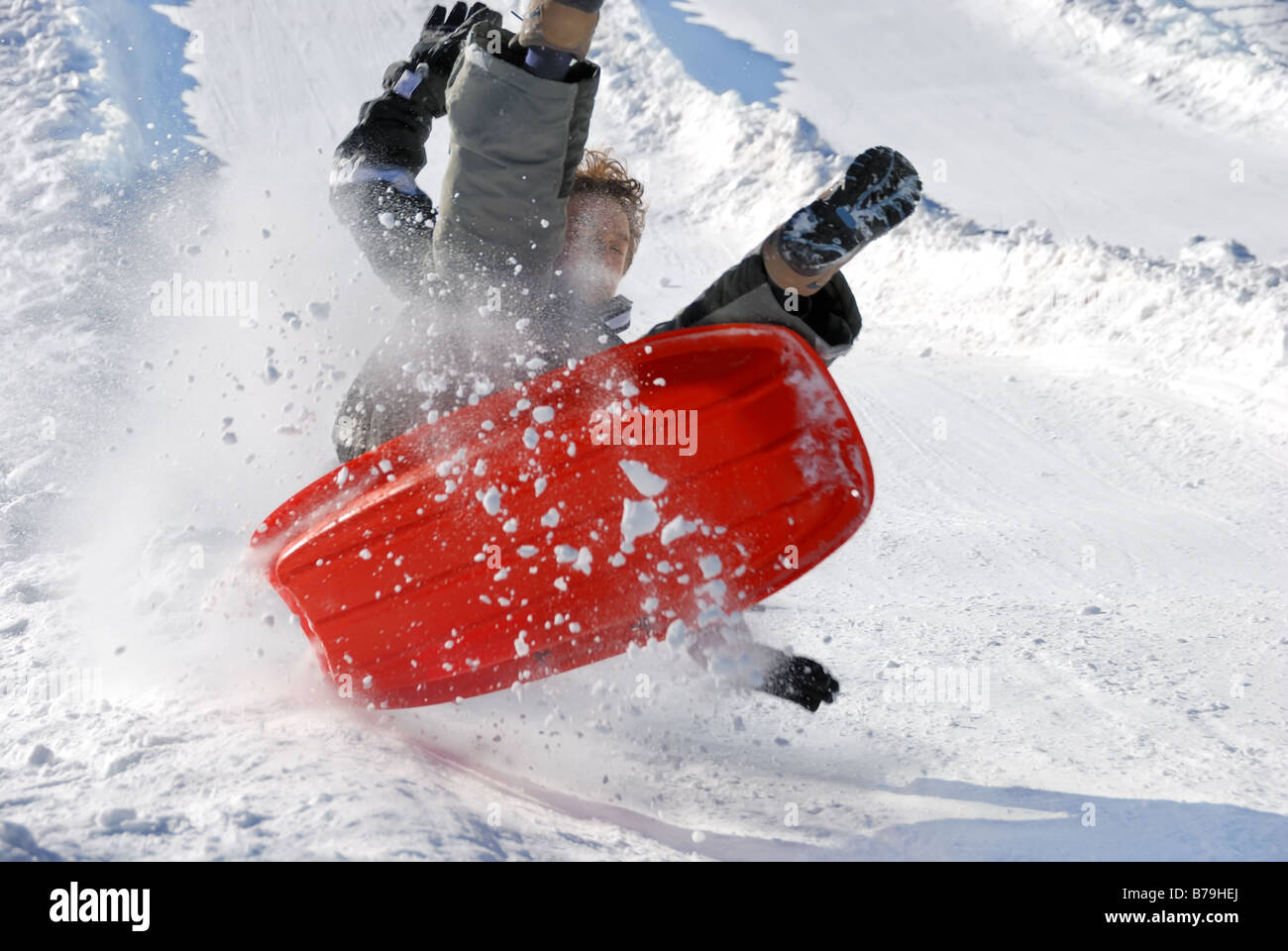 Junge in der Luft beim Rodeln schnell hinunter die Hilll mit Schnee Hintergrund Stockfoto