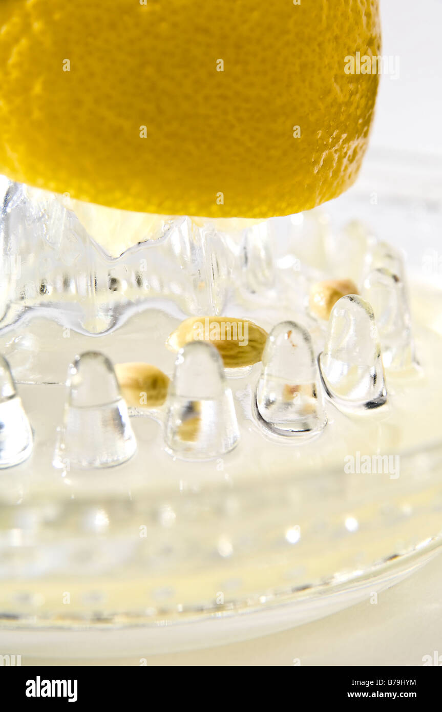 Zitrone gequetscht in eine Zitronenpresse. Das Design des Glas-Squeezer hält die Kerne zurück, so dass der Saft abgegossen werden kann. Stockfoto