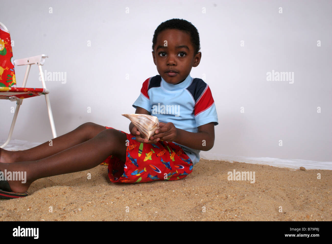 African American Boy Spielen im Sand mit einer Muschel Stockfoto