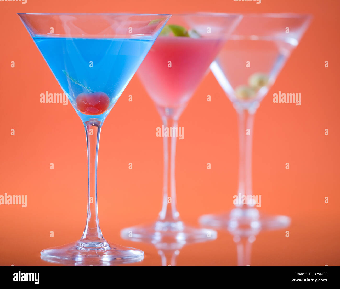 Farbe in Martini-Glas. Betty Blue, Cosmopolitan und Dry Martini Cocktails über bunte orange Hintergrund. Stockfoto