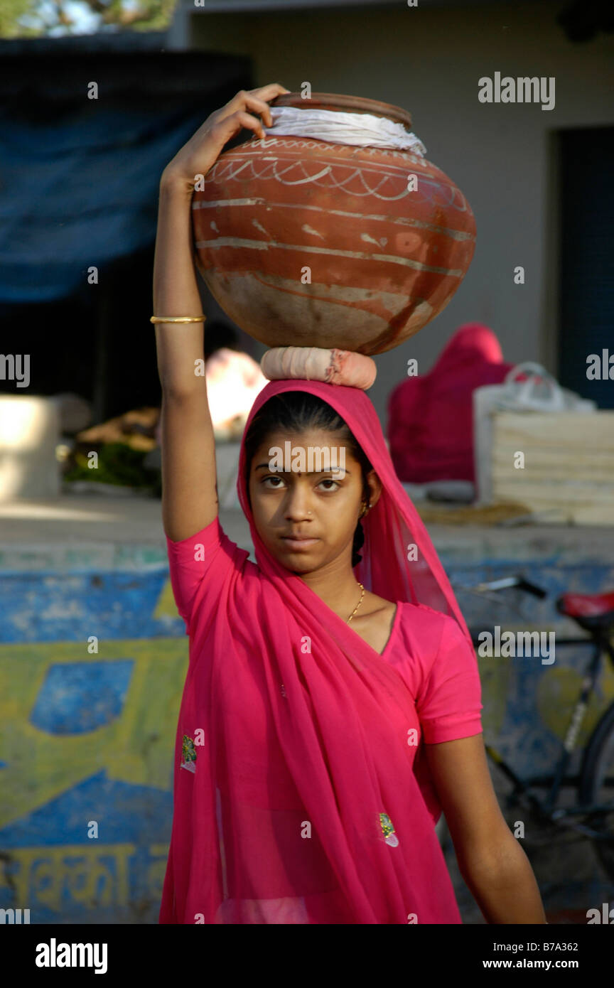 Junge indische Frau trägt einen Sari tragen eine bemaltem Ton-Kanne mit Wasser auf dem Kopf, Ghanerao, Rajasthan, Indien, Asien Stockfoto