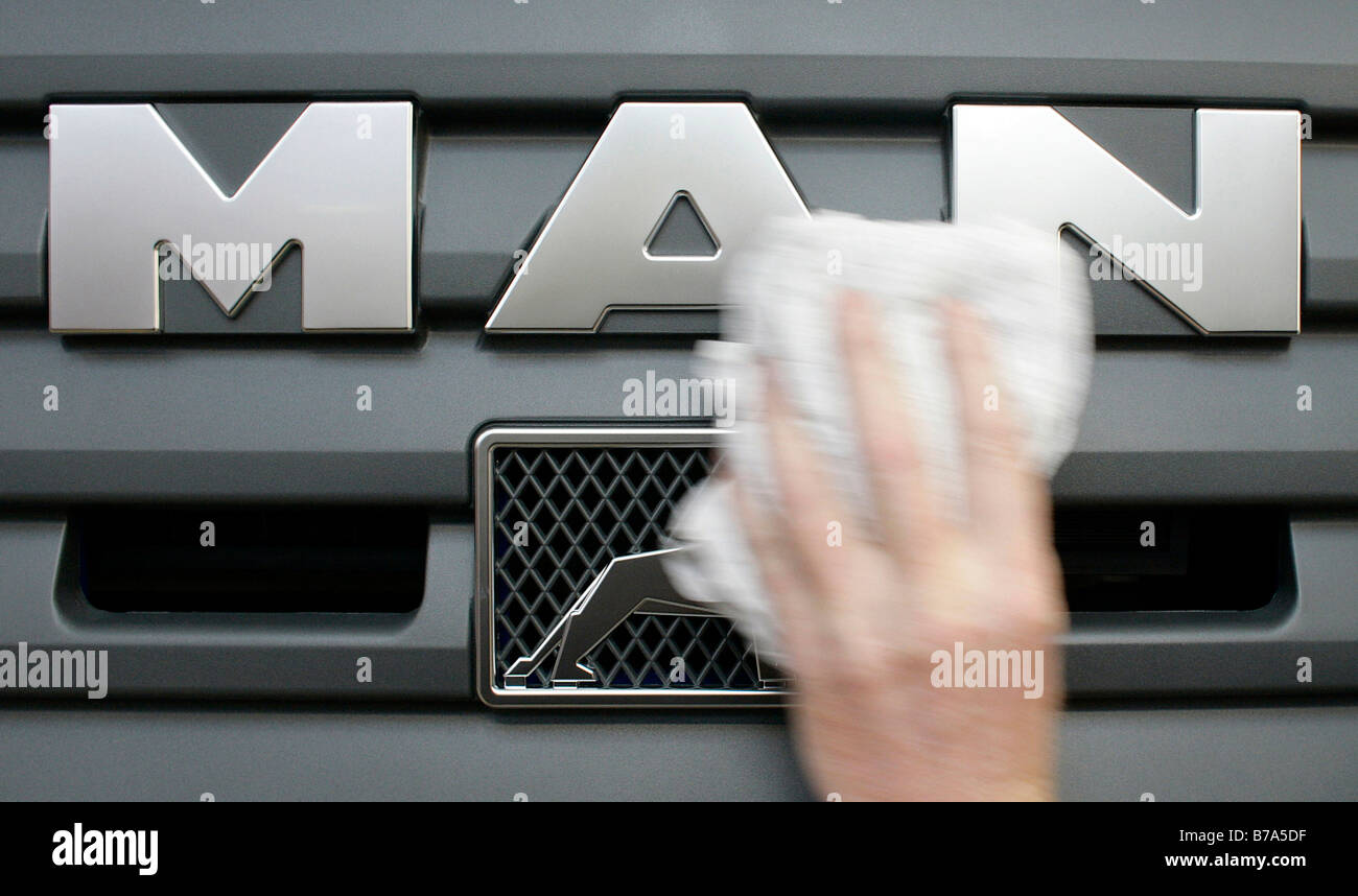 Eine Hand Polieren, Reinigung des Firmenlogos auf dem Kühlergrill eines Lastwagens, Herstellung, Produktion Mann Nutzfahrzeug Korpora Stockfoto