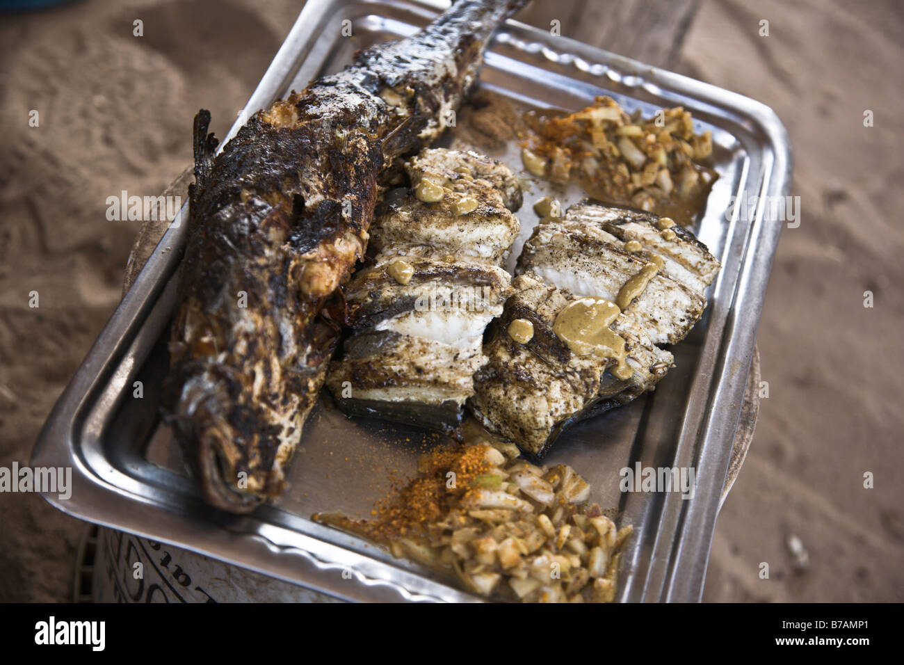Frisch gegrillter Fisch, garniert mit Senf und einer Seitenlänge von Zwiebeln und Gewürzen serviert an einem Strand Fisch Stand in Yoff, Senegal Stockfoto