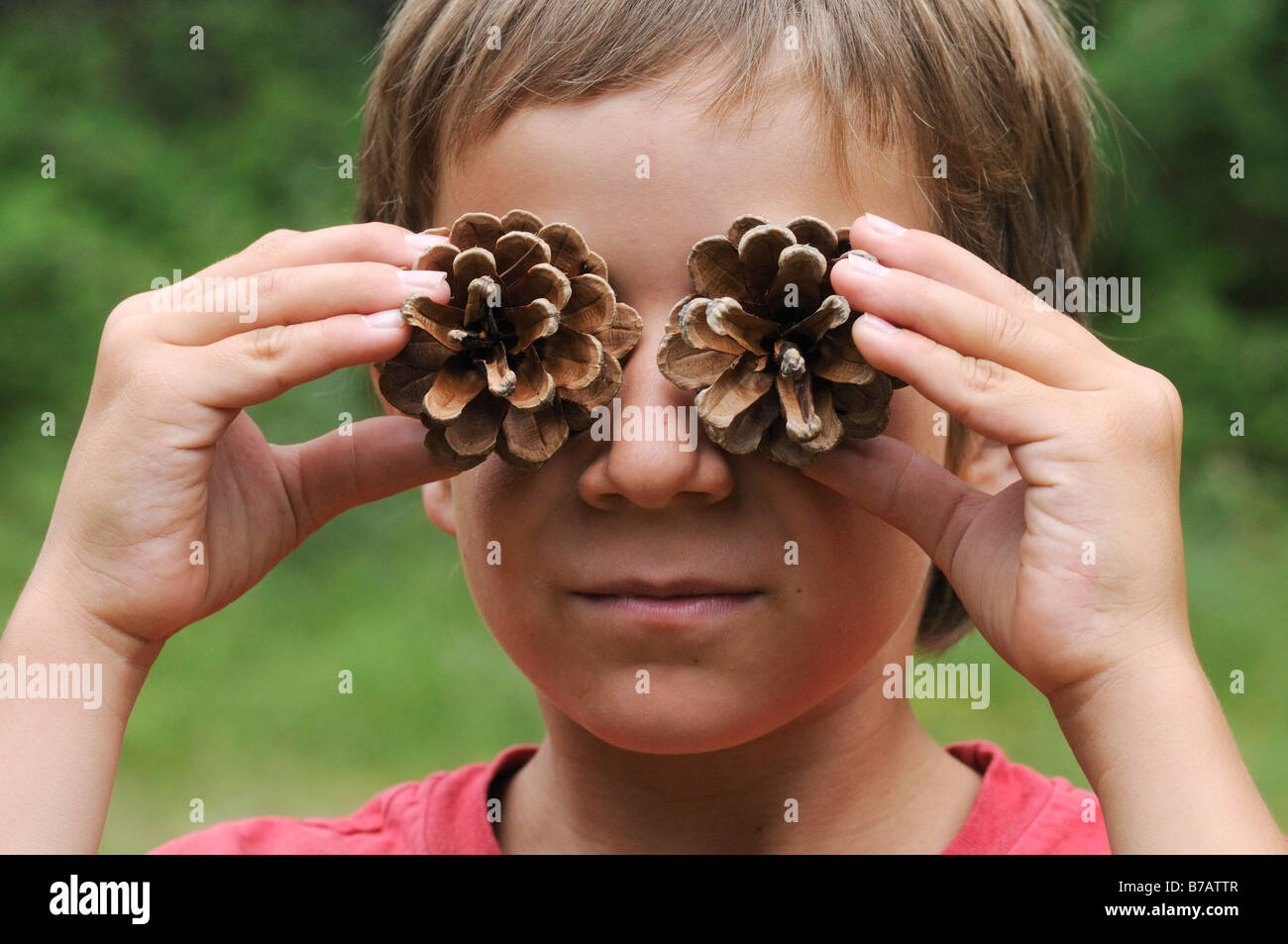 Junge mit Tannenzapfen vor Augen Stockfoto