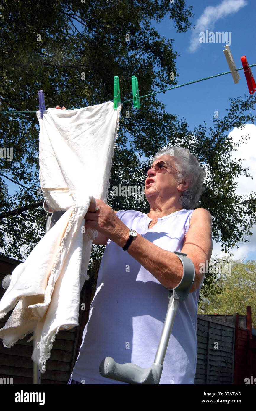 Ältere Frauen mit Behinderung hängt ihre Wäsche draußen trocknen Leeds, West Yorkshire Stockfoto