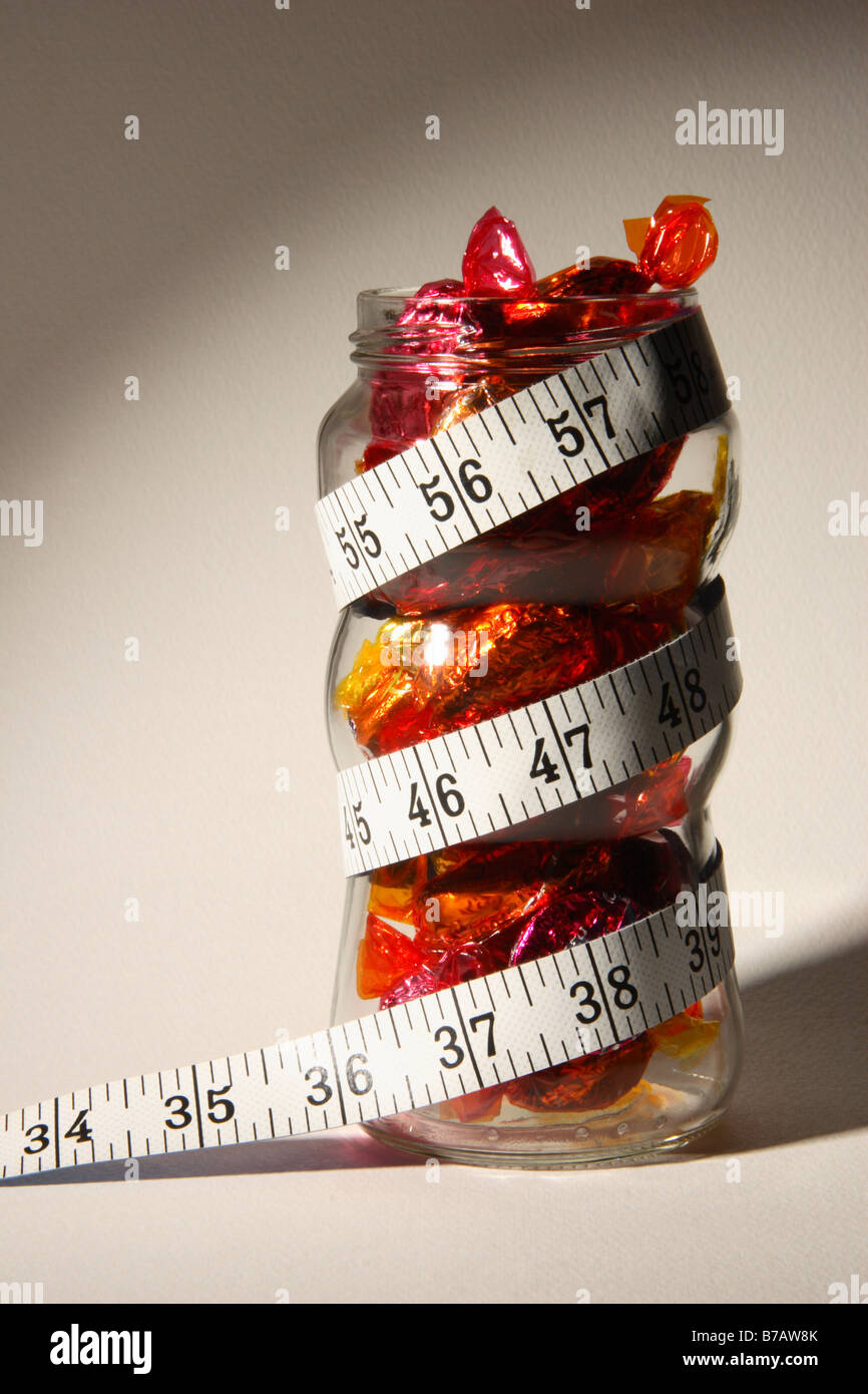 Ein süßes Glas voller Schokolade mit einem spiralförmigen Maßband. Stockfoto