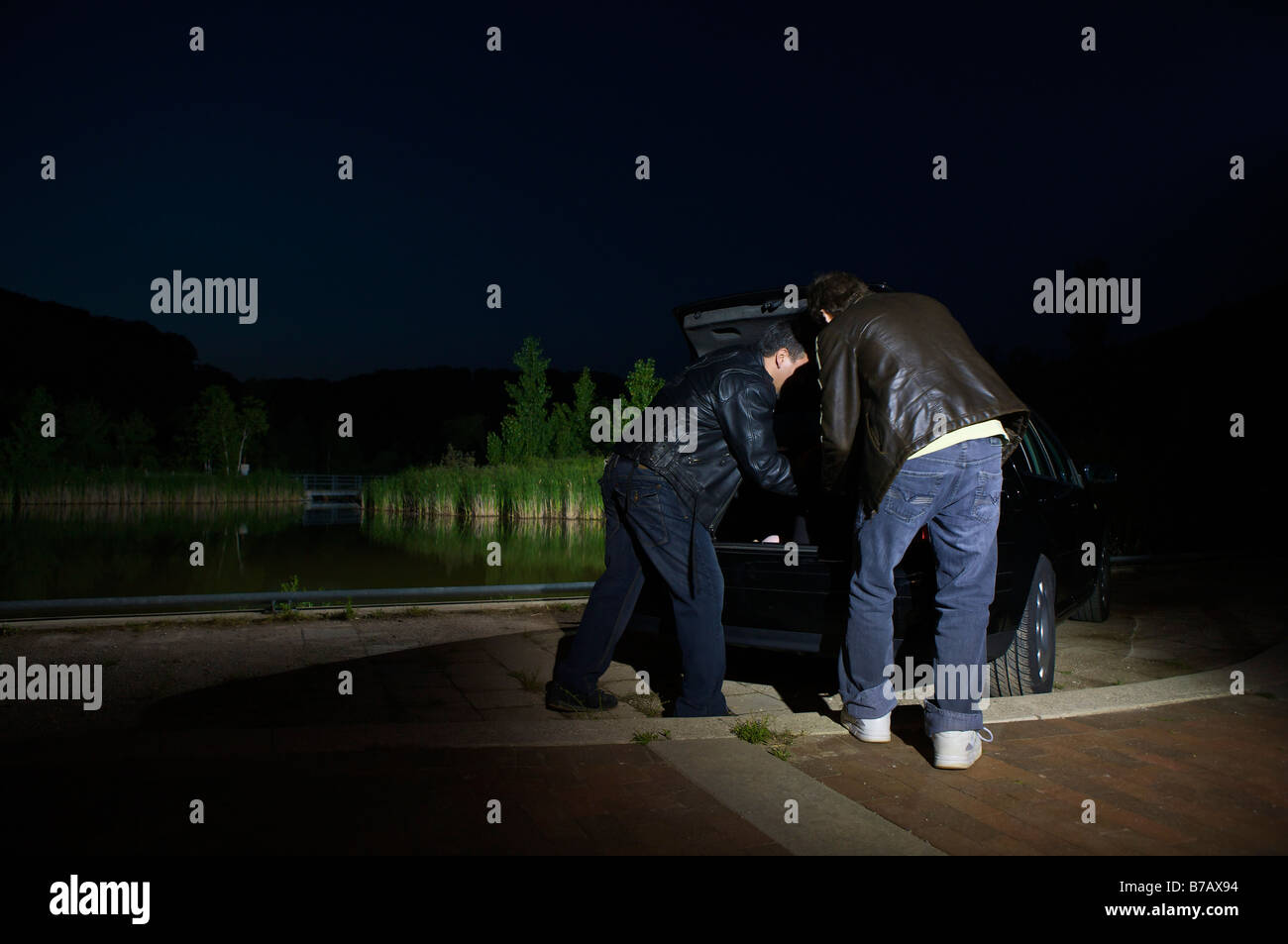 Männer, die etwas aus dem Kofferraum eines Autos in der Nacht zu entfernen Stockfoto