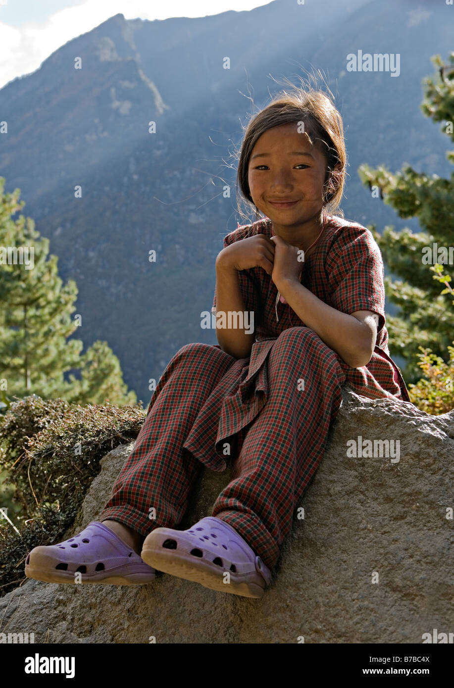 Porträt von einem freundlichen nepalesische Mädchen sitzt auf Felsen in Namche Bazar Dorf in Sagarmatha National Park Khumbu-Region Nepal Stockfoto