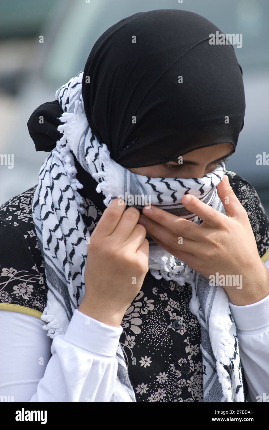 Die junge palästinensische Frau bedeckt ihr Gesicht mit einem traditionellen schwarz-weißen Fischnetz-Keffiyeh oder kufiya-Schal Stockfoto