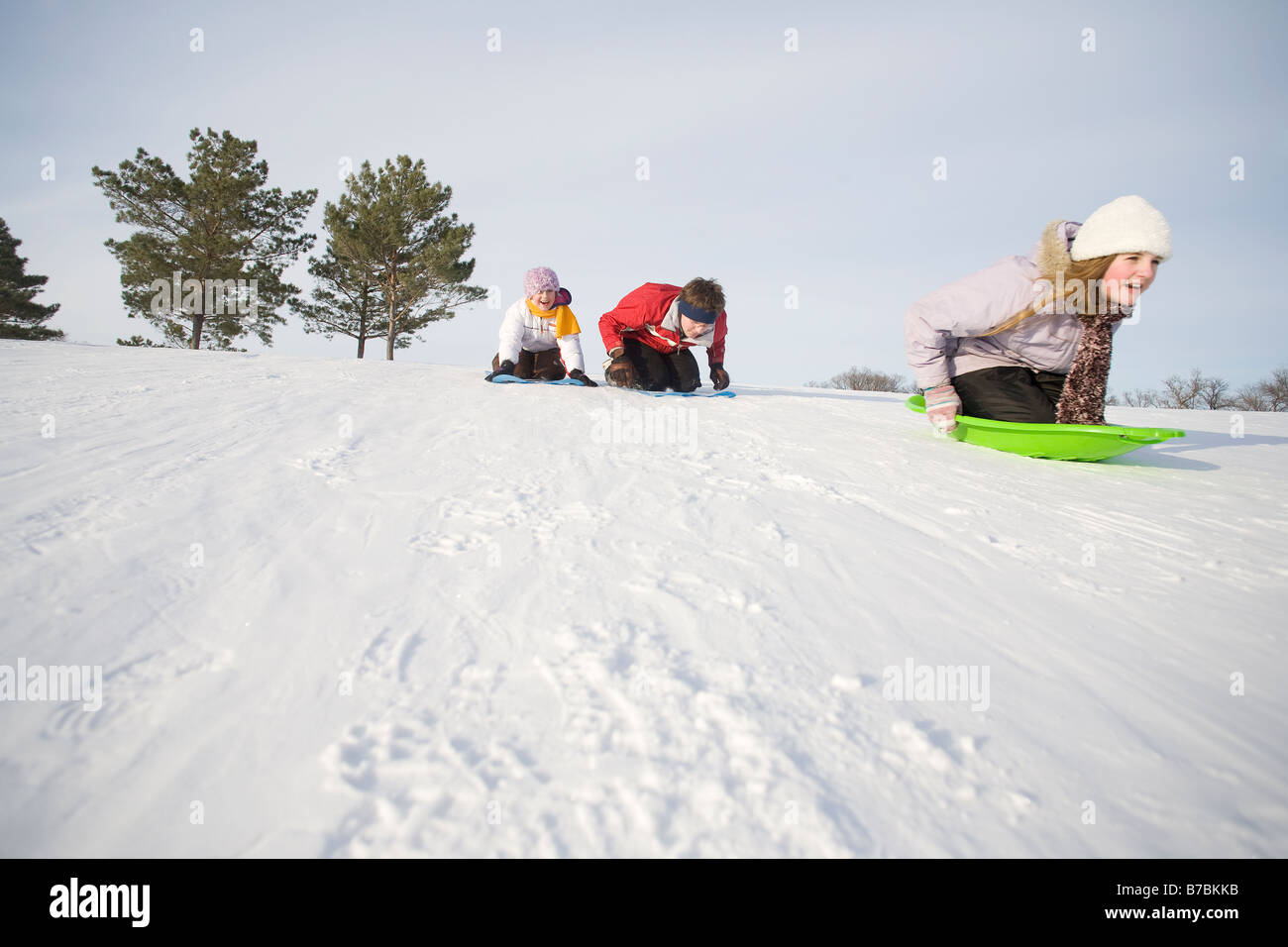 3 Kinder (14, 13 und 9 Jahre alt) rutschen bergab, Winnipeg, Kanada Stockfoto