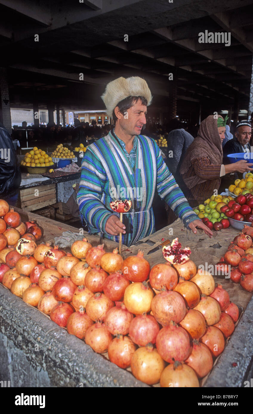 Mann in Pelzmütze Verkauf Granatäpfel und Äpfel Kolhoznaya bedeckt Basar Samarkand Uzbekistan Asien Basar ist gegen gedrückt. Stockfoto