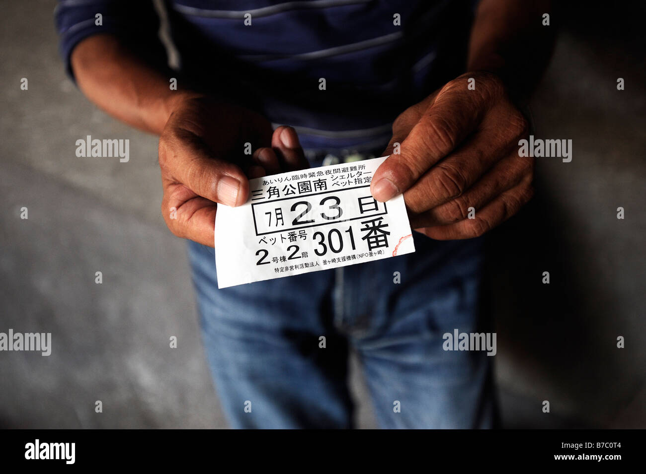"Koji" Yamaguchi zeigt dem Ticket erhielt er seine Bett-Nummer in einem Tierheim für Obdachlose und Tagelöhner angibt. Stockfoto