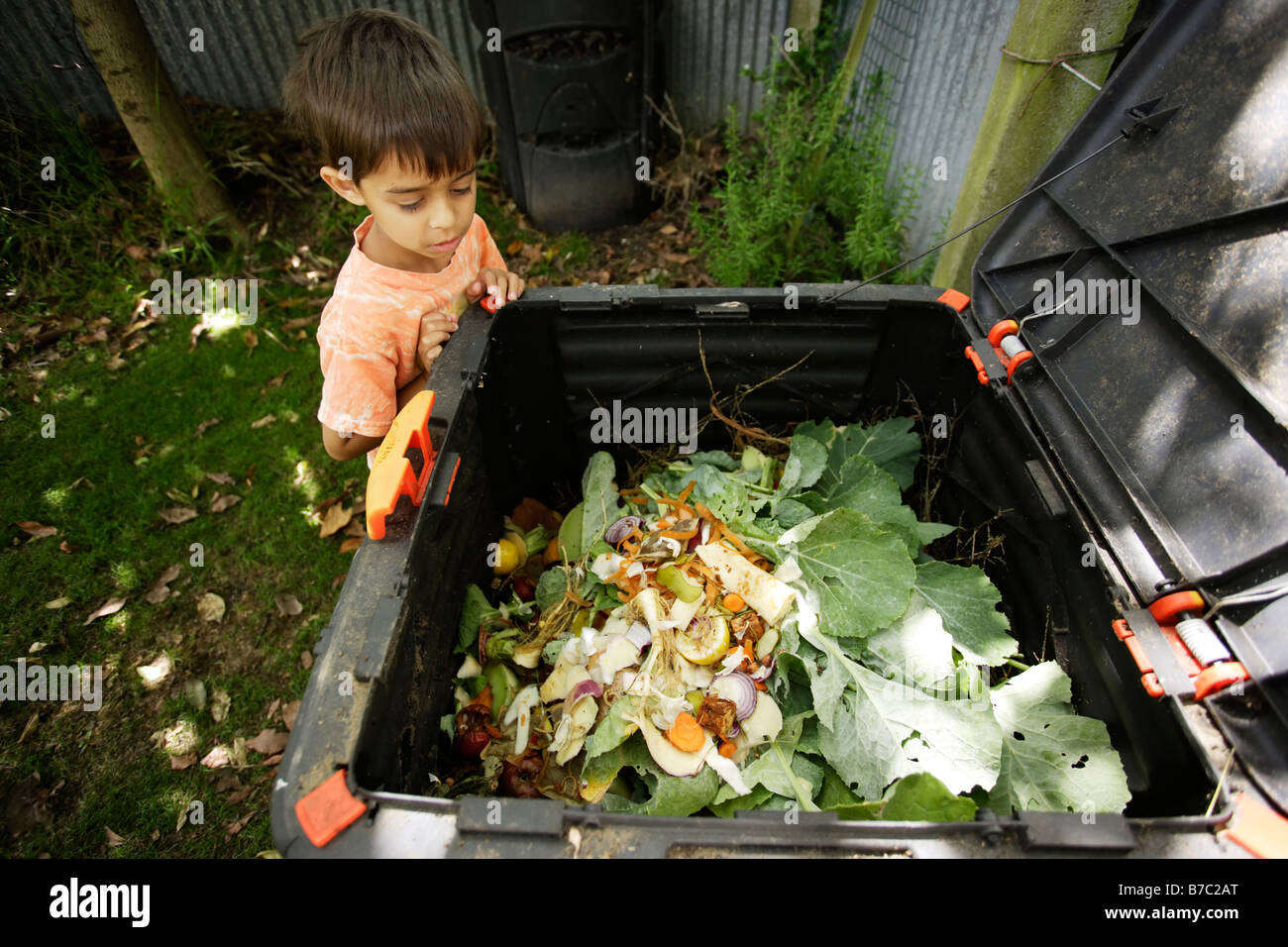 Sechs Jahre alter Junge examiniert Kompost im Garten Stockfoto