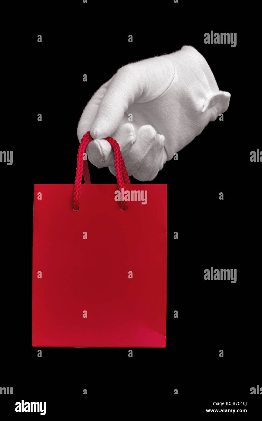 Eine Hand in einen weißen Handschuh hält eine rote Einkaufstasche isoliert auf schwarz Stockfoto