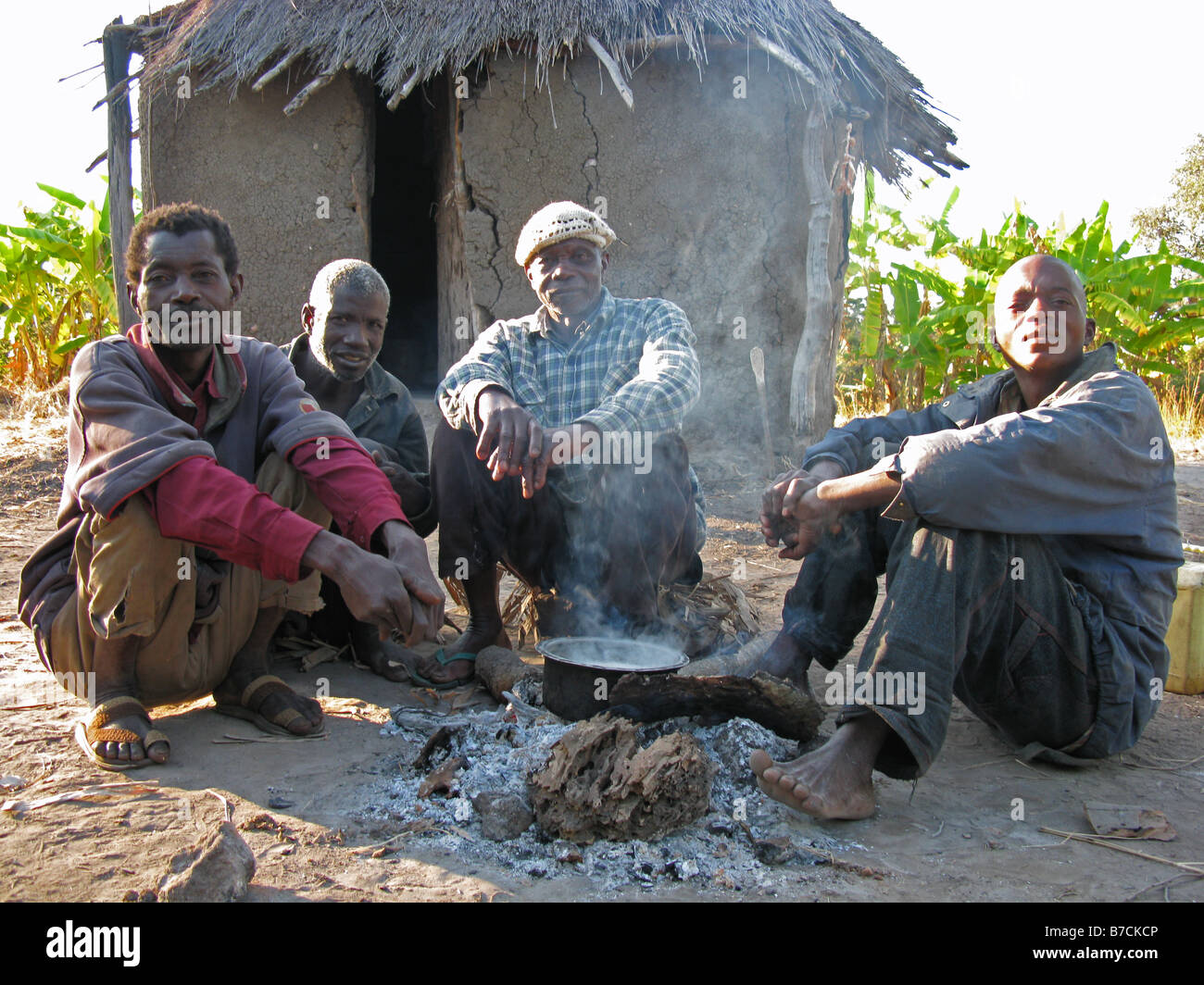 Vier deutschsprachige Fischer wärmten sich um Camp am frühen Morgen Chambeshi Feuer Bemba Wohnungen Nord-östlichen Sambia Stockfoto