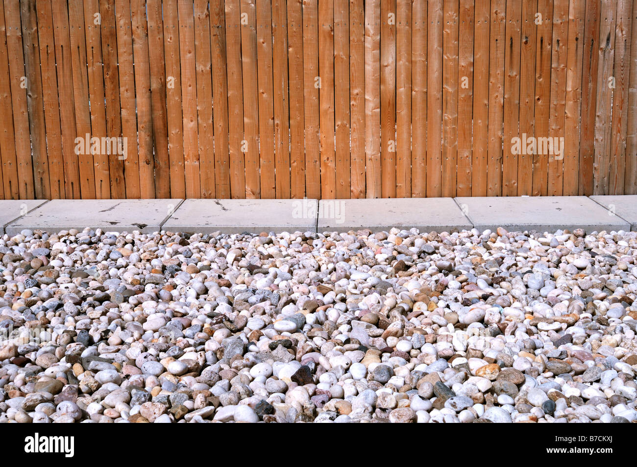 Ein Holzzaun, betonierten Weg und vielen kleinen Steinen. Horizontale Stockfoto