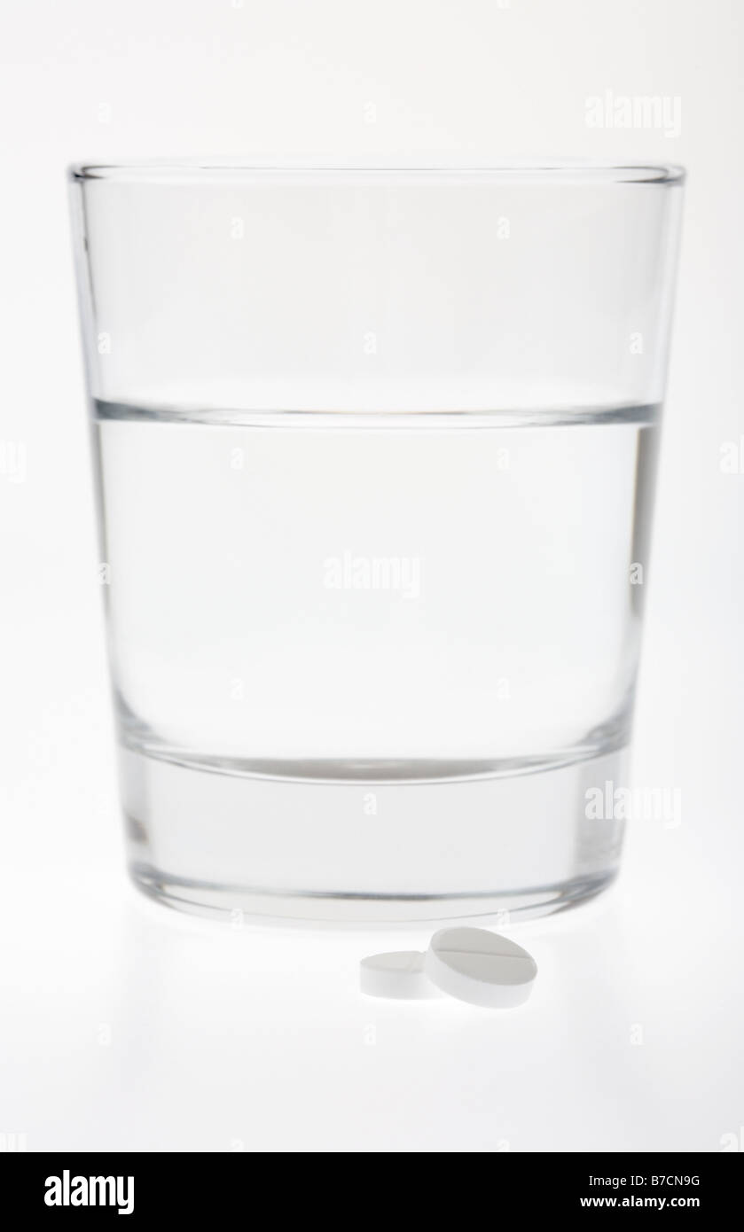 Glas halb voll leer mit Wasser mit zwei Paracetamol Tabletten isoliert auf weißem Hintergrund Stockfoto
