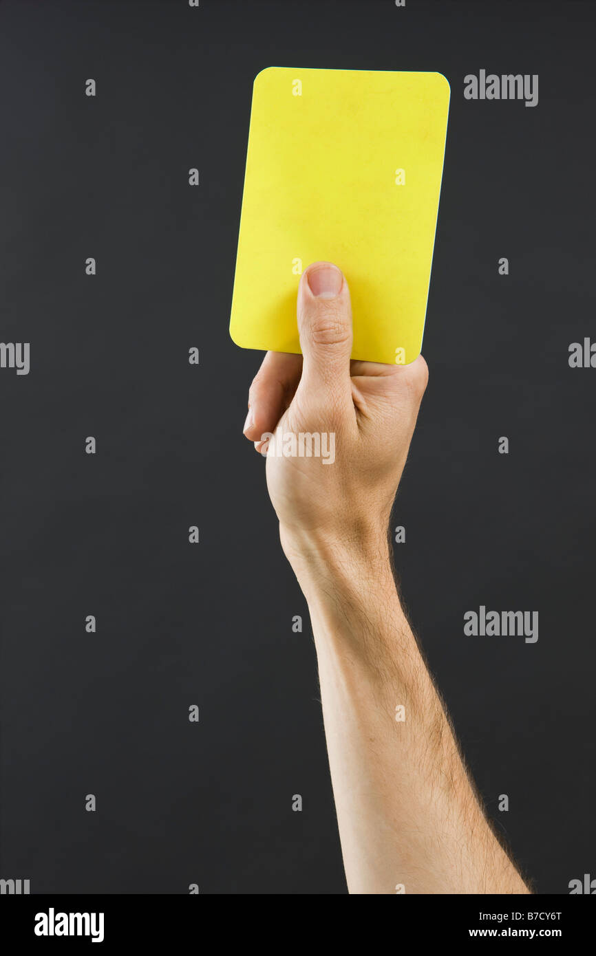 Eine Hand hält eine gelbe Karte Stockfoto Eine Hand hält eine gelbe Karte Stockfoto