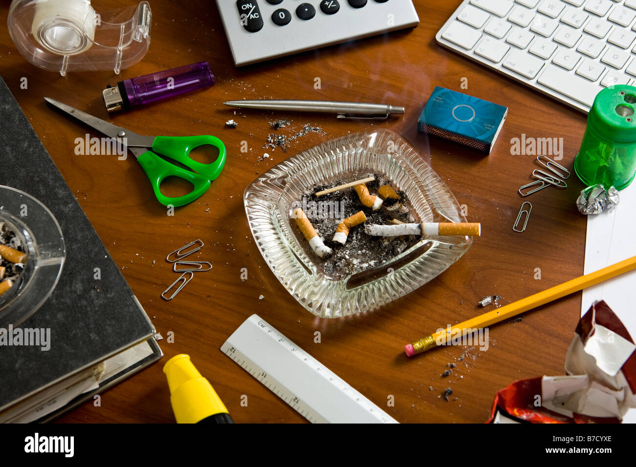 Ein Schreibtisch überladen mit Büromaterial und Aschenbecher ...