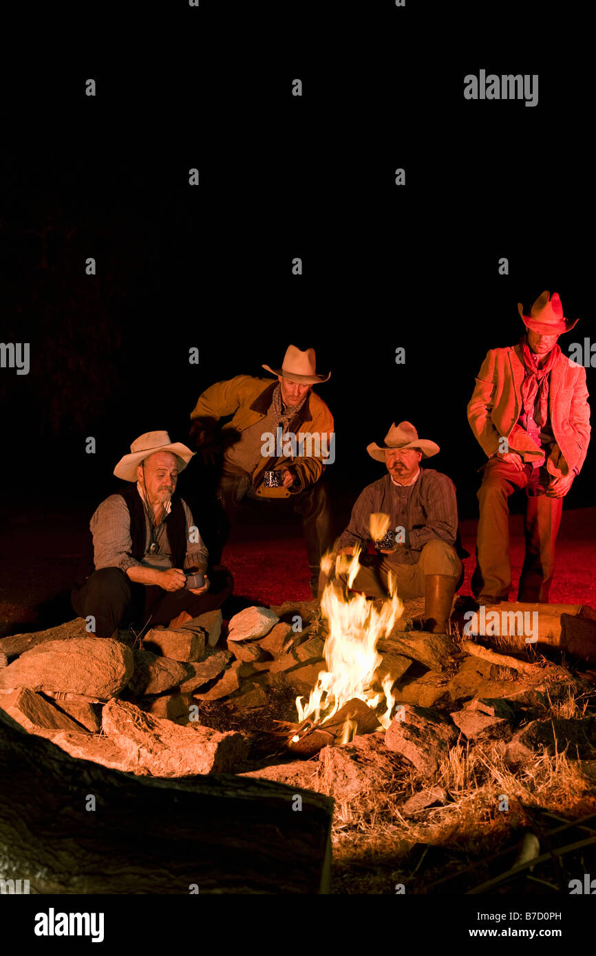 Cowboys sitzen um ein Lagerfeuer am Abend Stockfoto