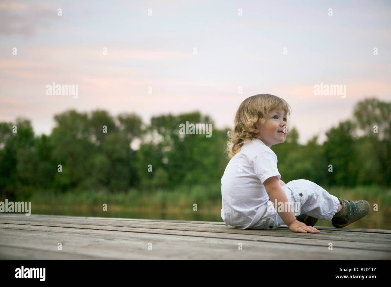 Eine lächelnde junge sitzt auf einem Steg Stockfoto