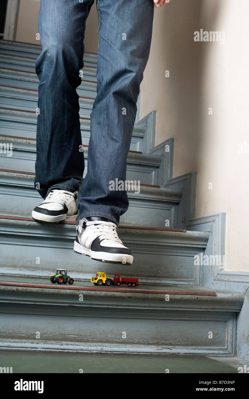 Ein Mann Treppen hinunter zum Schritt auf Spielzeugautos Stockfoto