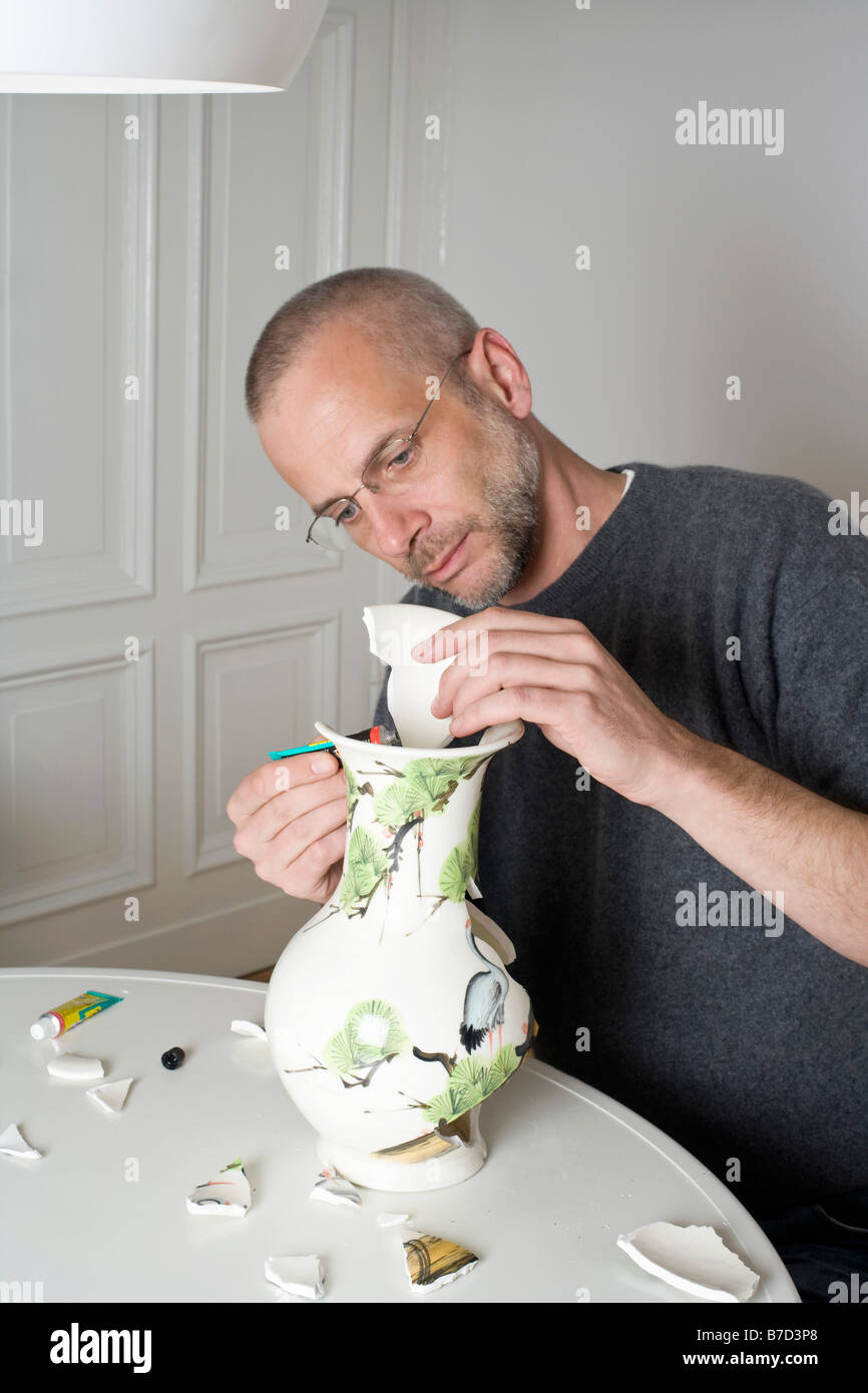 Ein Mann, eine zerbrochene Vase reparieren Stockfoto