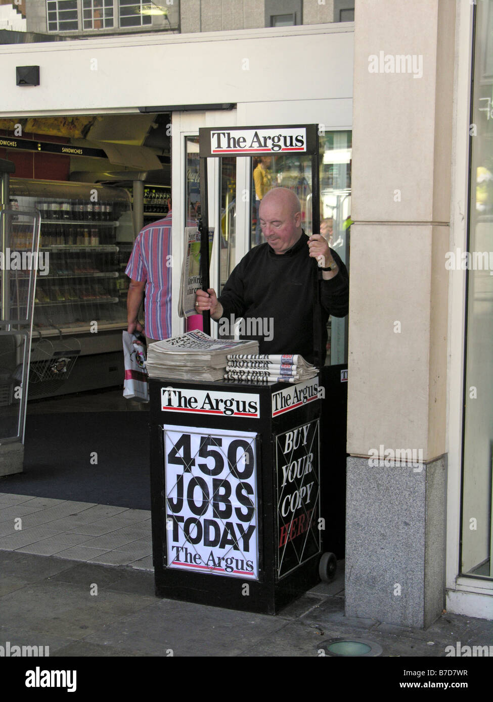 älterer Mann verkauft die Argus Zeitung in Churchill Square Brighton East Sussex Stockfoto