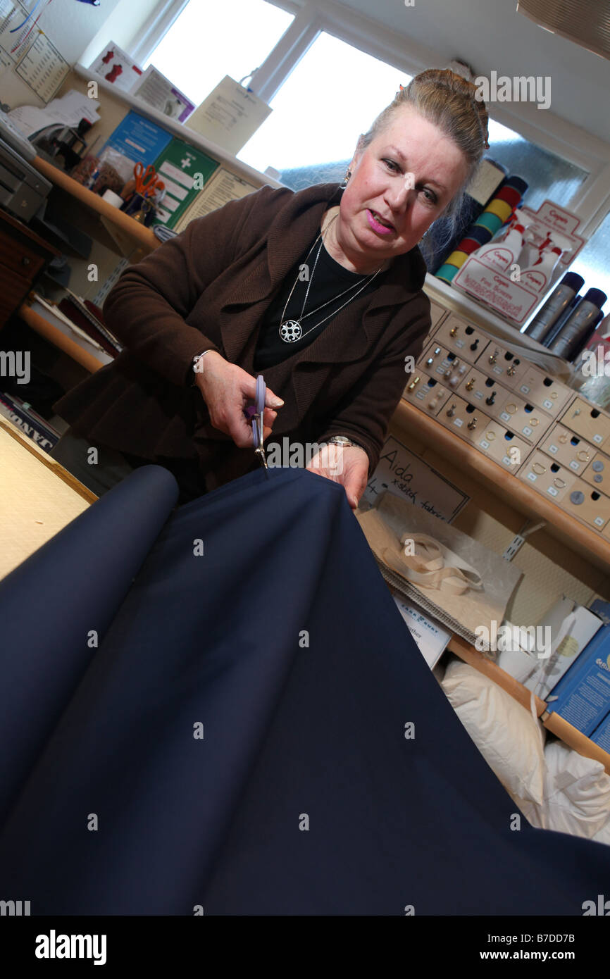 eine professionelle Schneiderin schneiden einige blaue Material, eine modische Kleidung für einen Kunden Stockfoto