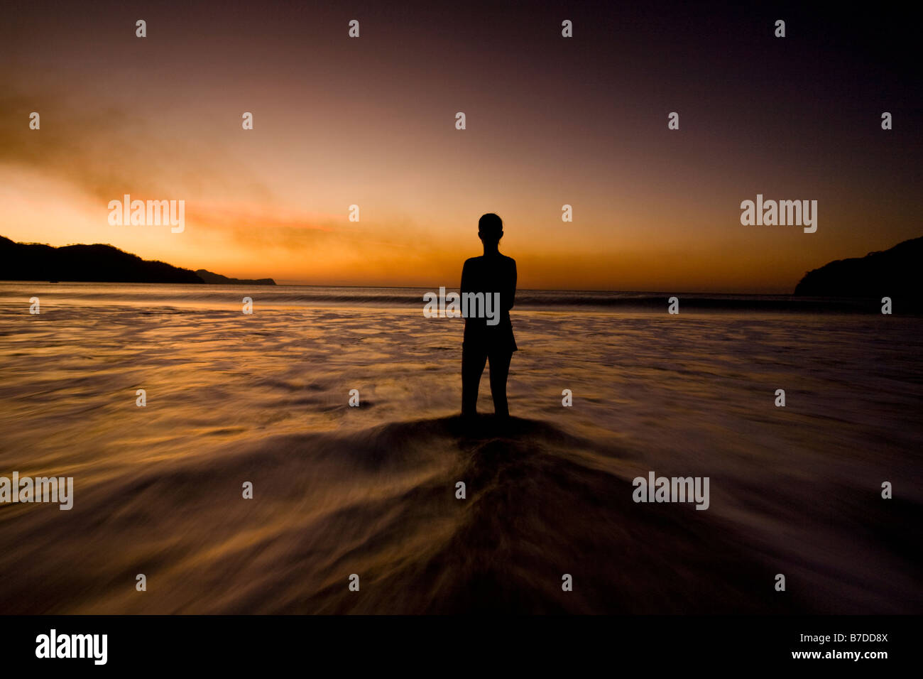 Silhouette der jungen Frau, die in das Wasser am Strand den Sonnenuntergang in Playas del Coco, Costa Rica. Stockfoto
