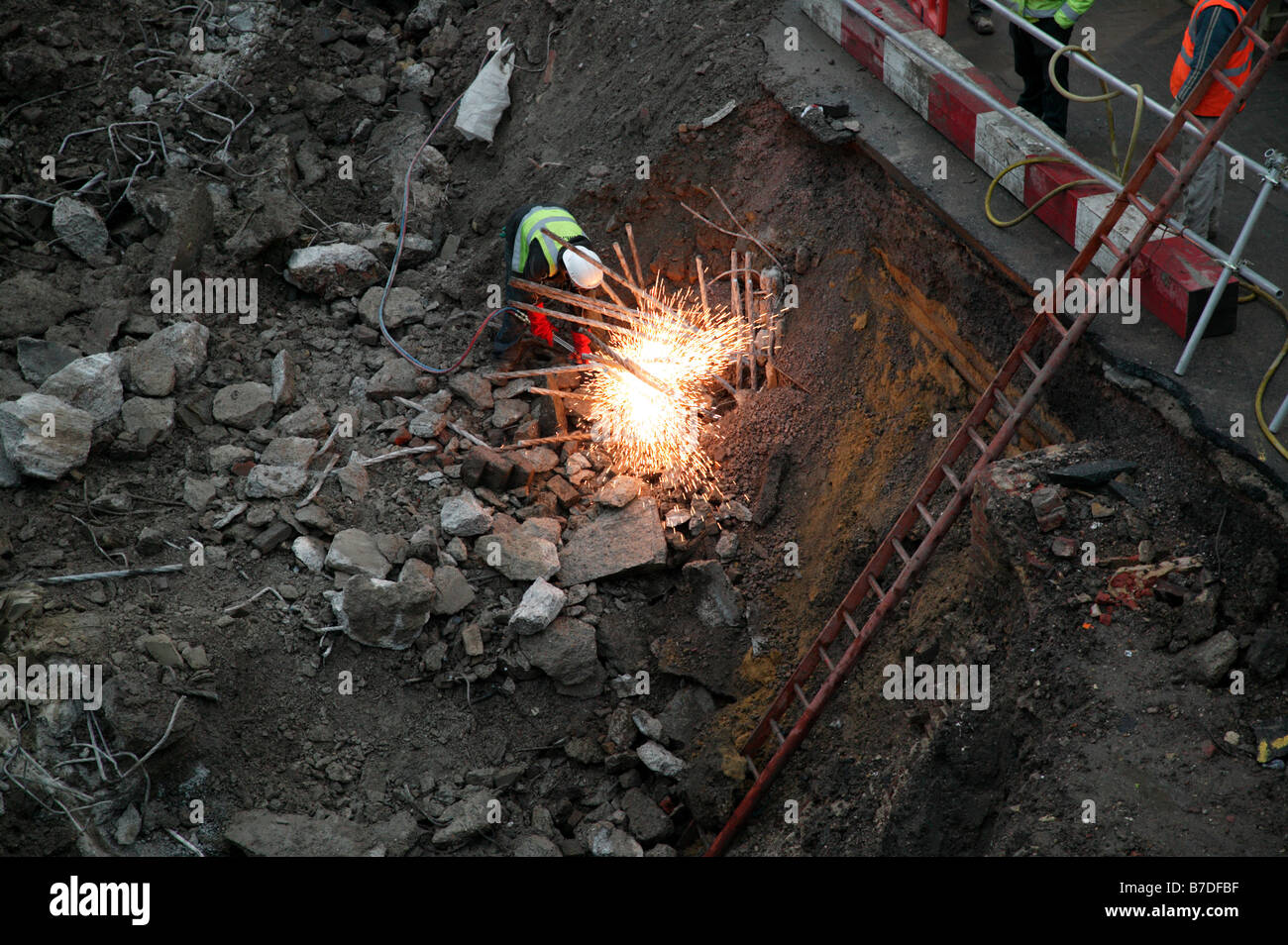 Ein Arbeiter mit Autogen schneiden um Stahl Bewehrungsstäbe zu entfernen, nachdem der Beton mit einer Ramme entfernt worden war Stockfoto