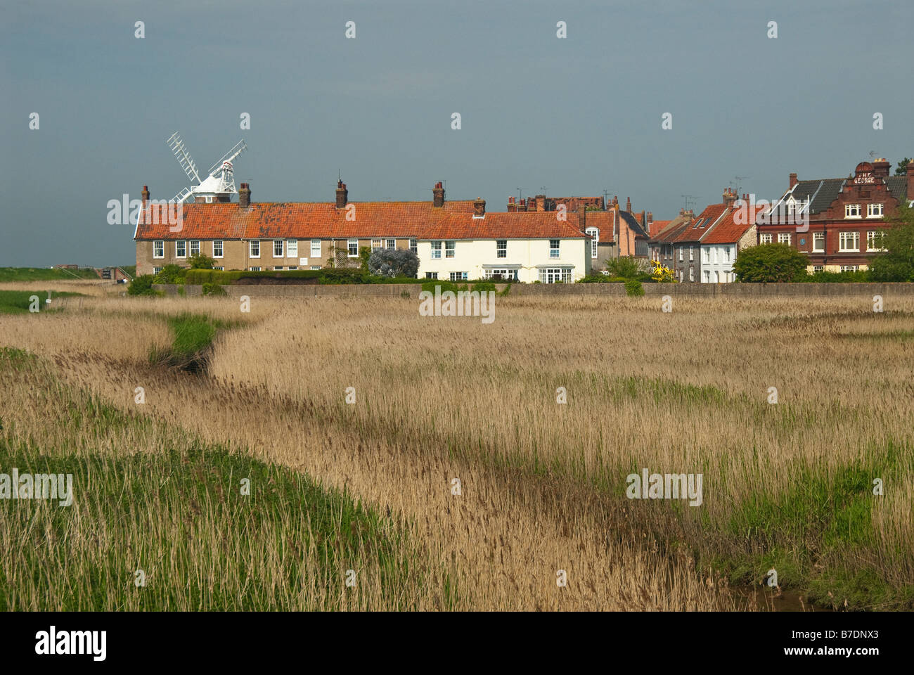 Ein Blick über Sümpfe gegenüber den Feuerstein und rotem Backstein Häuser Cley als nächstes am Meer mit Cley Mill im Hintergrund. Norfolk. VEREINIGTES KÖNIGREICH. Stockfoto