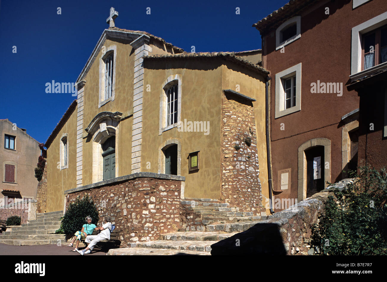 Frauen im Chat unter Kirche & Dorfplatz, Roussillon, Regionalpark Luberon, Provence, Frankreich Stockfoto