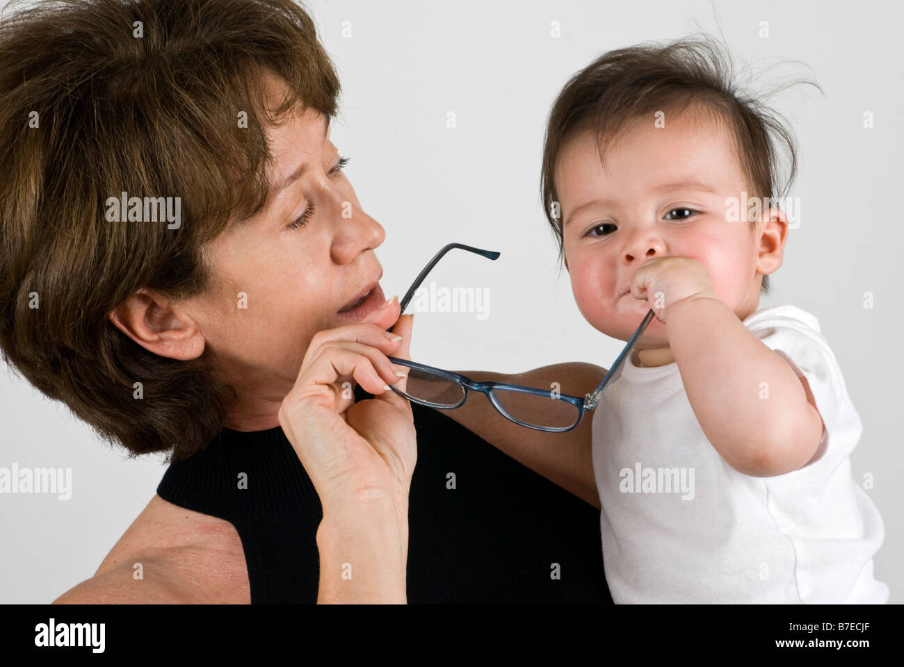 Eine Großmutter verliert ihre Lesebrille auf den Griff ihrer kleinen Enkelinnen Hände Stockfoto