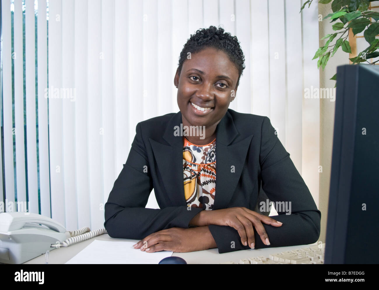 Eine schöne junge schwarze Frau in einer Büroumgebung eine Art freundlich Lächeln Stockfoto