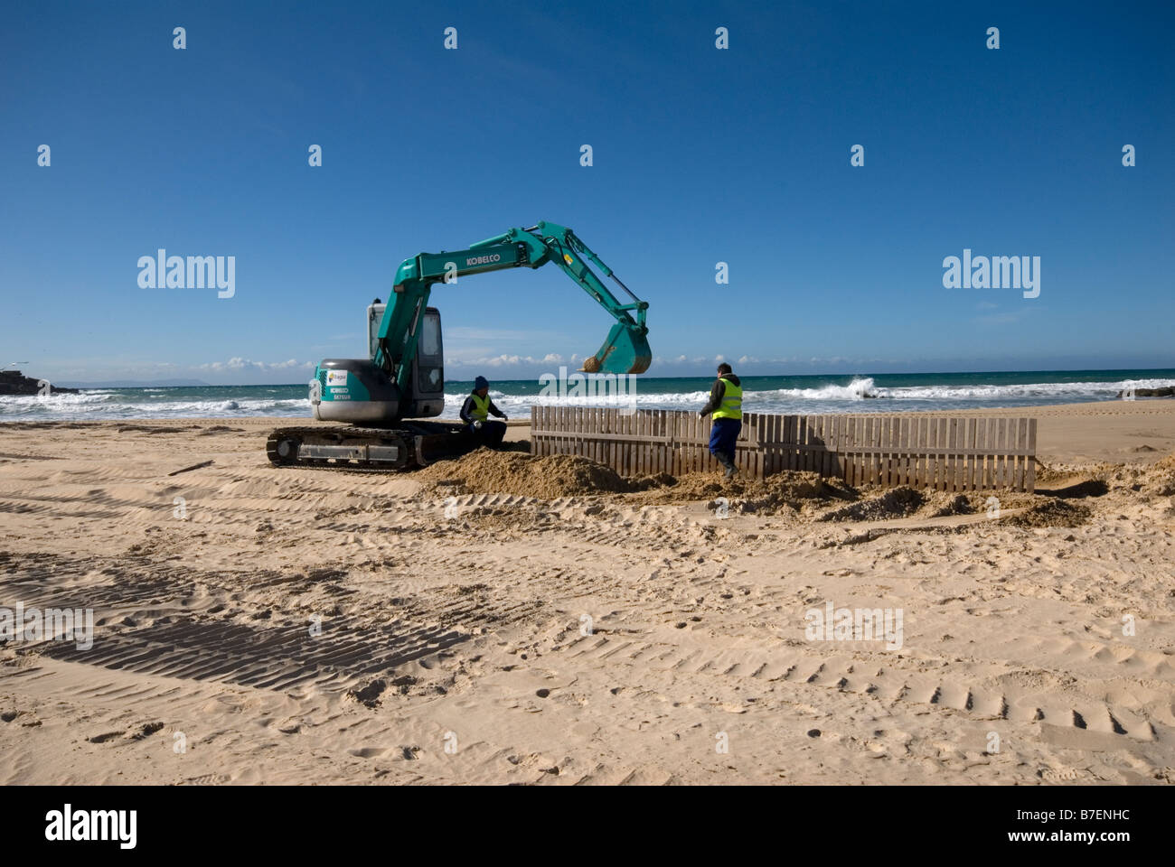 Bauarbeiter Regie Fahrer grabende Gräben in Strand anti-Erosion Barrieren einfügen Stockfoto