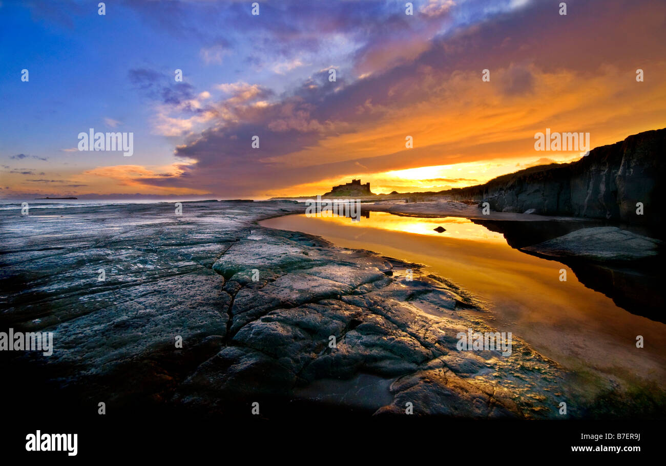 Sonnenaufgang über den Strand und Burg von Bamburgh Castle in Northumberland Küste Stockfoto