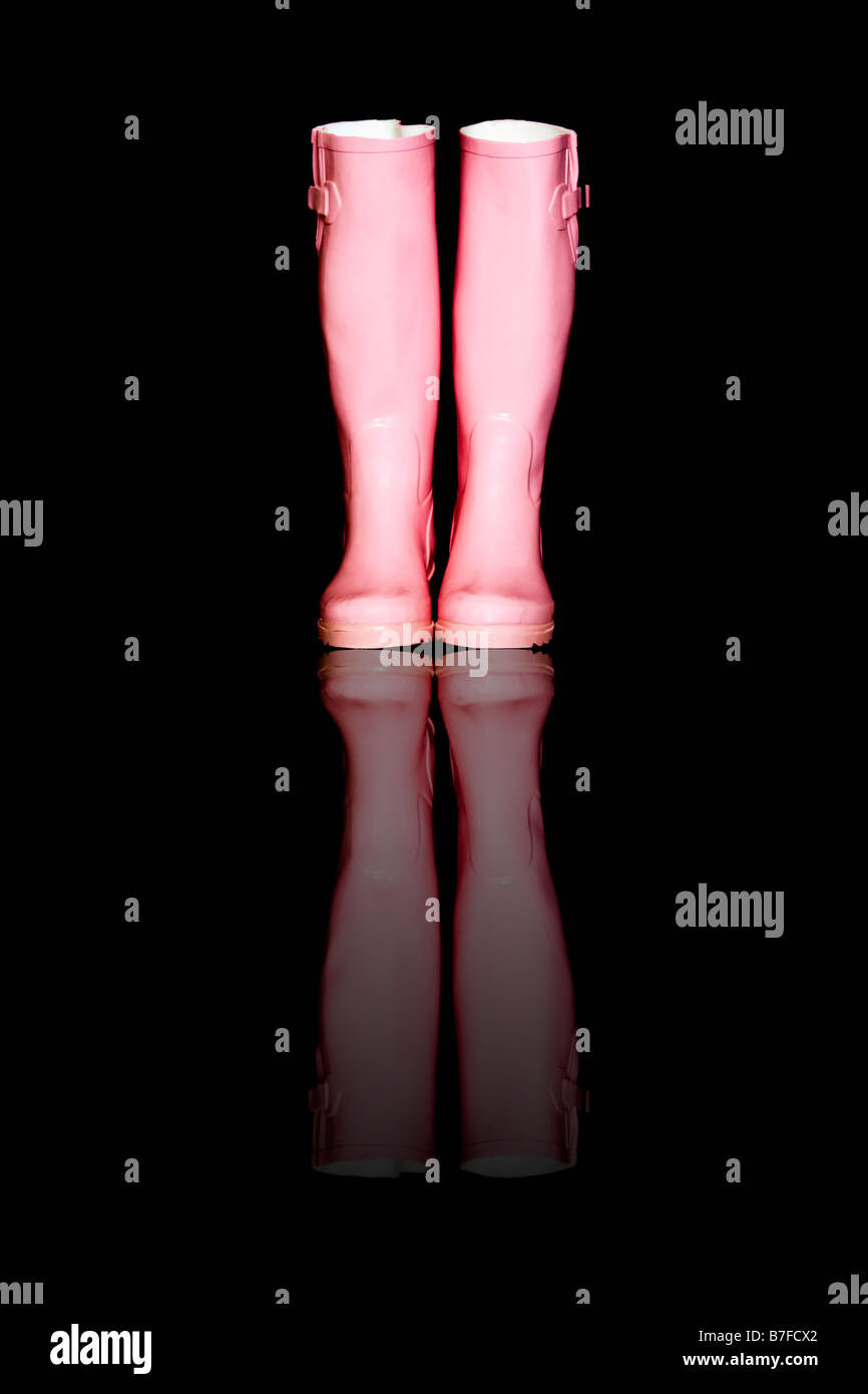 Ein paar rosa Gummistiefel oder Gummistiefel gegen einen schwarzen Hintergrund mit Reflexion Digital hinzugefügt Stockfoto