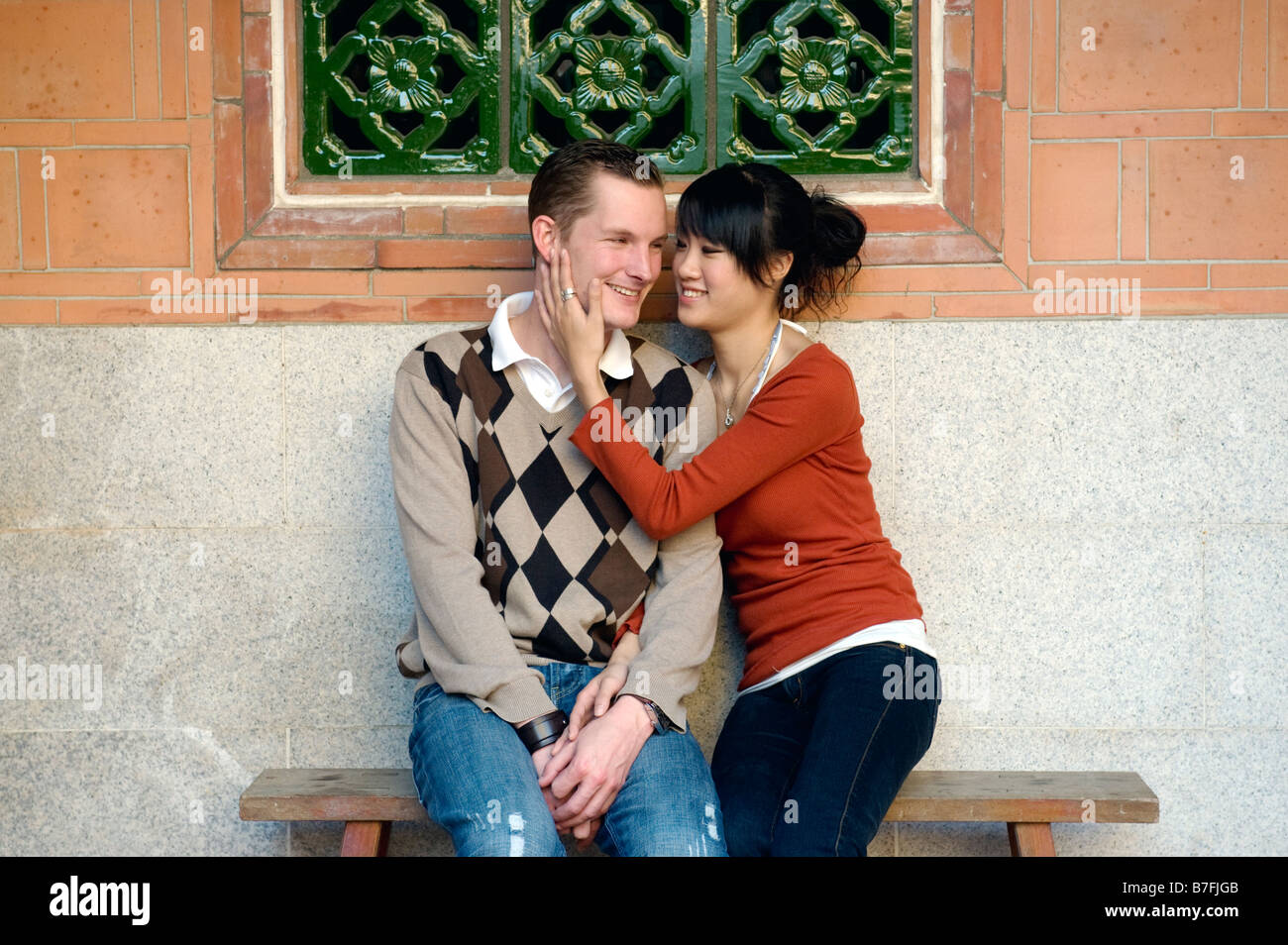 Junges Paar auf Bank halten einander In traditionellen chinesischen Park, Taiwan Stockfoto