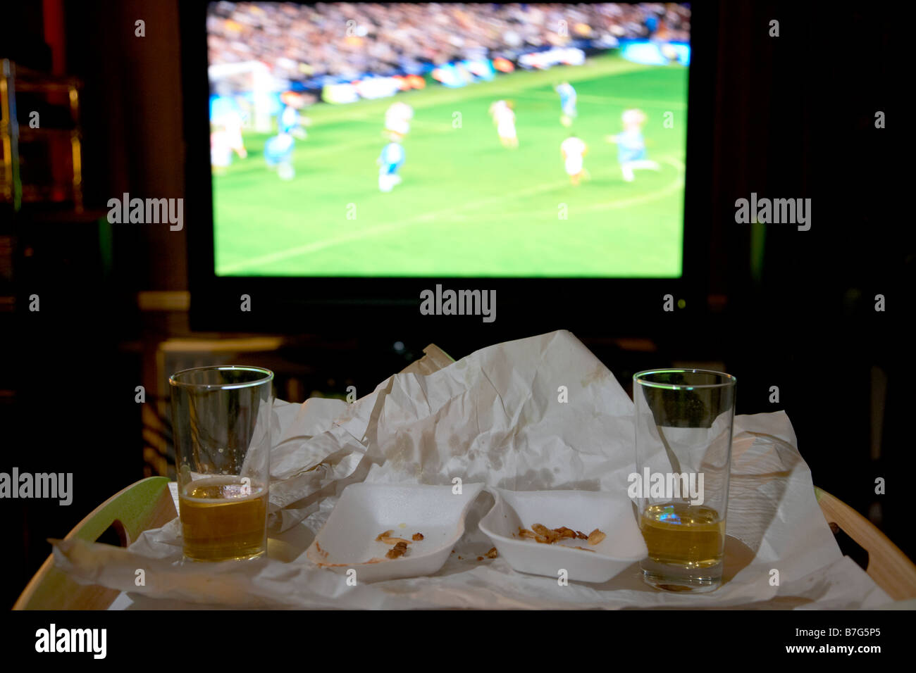 bleibt ein Imbiss Mahlzeit für zwei Personen und Gläser Bier auf einem Tablett vor Fußballspiel auf dem tv im Wohnzimmer eines Hauses Stockfoto