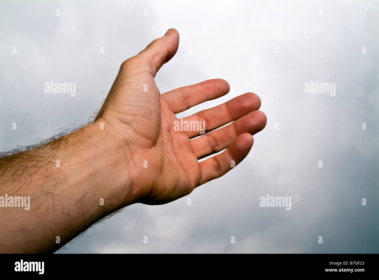 Ein Mann s Hand greift in den Himmel als ob brauchen eine helfende hand Stockfoto