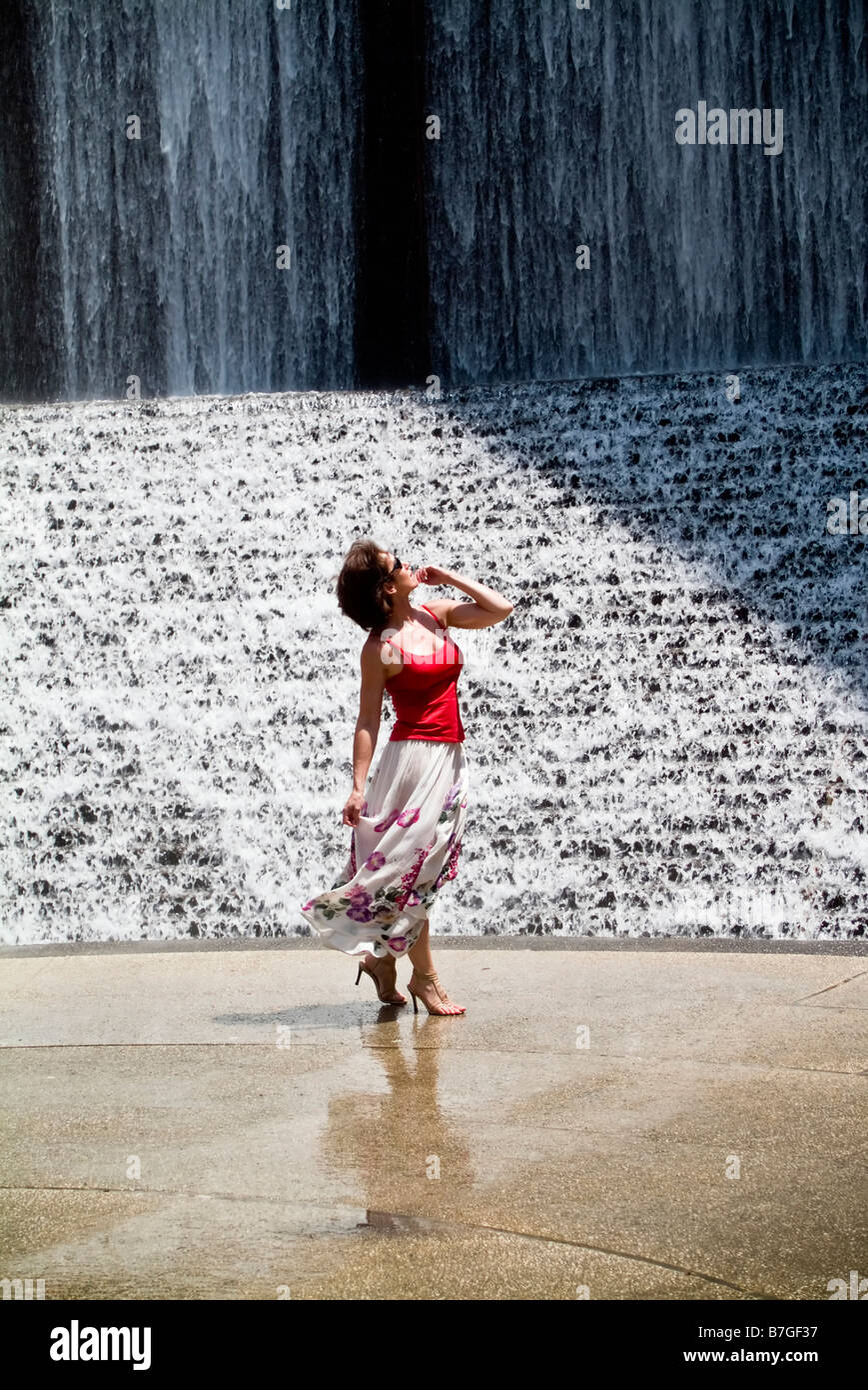 Eine Frau ehrfürchtig mit dem Glanz von einem künstlichen Gewässer-Wasserfall Stockfoto