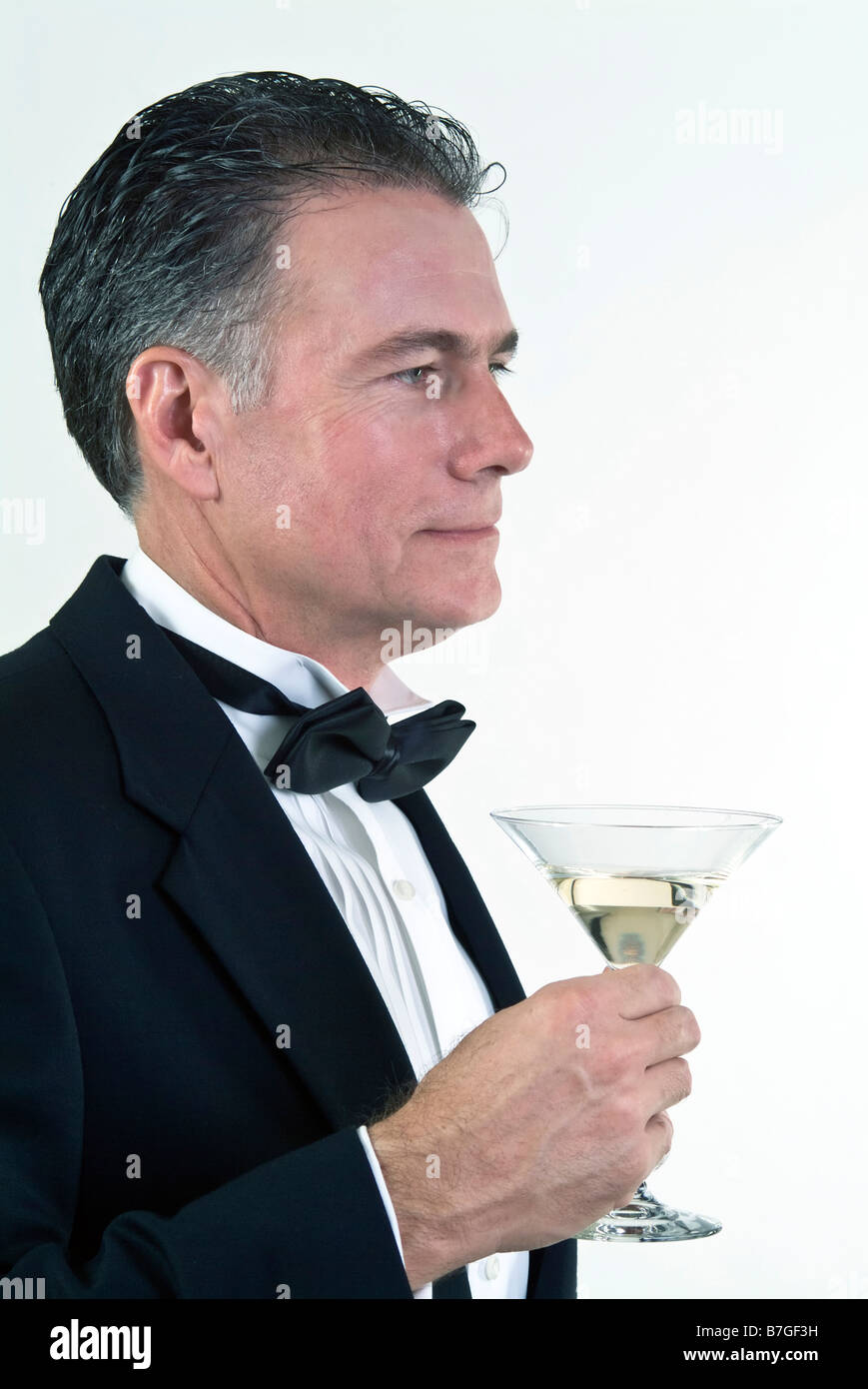 Ein Mann in formelle Kleidung und einen Martini Glas in seiner Hand Blick aus in die Ferne genommen auf weißem Hintergrund Stockfoto