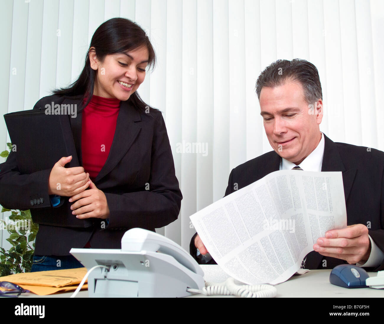 Eine junge Frau und ein Mann mit Blick auf ein Dokument auf Papier im legal-Format Stockfoto