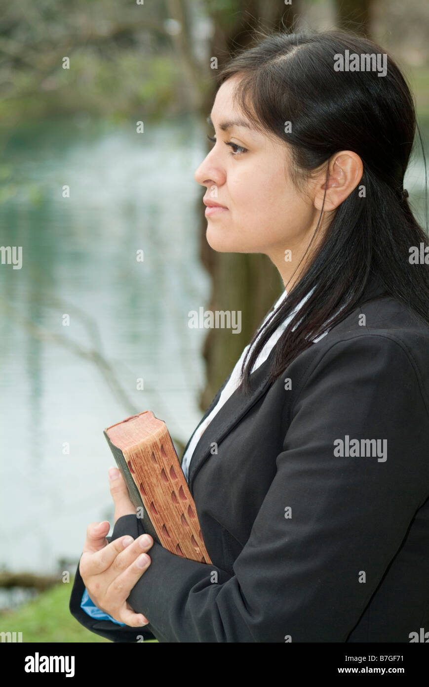 Eine junge Frau blickte in die Ferne, die halten, was scheint, eine Bibel zu sein Stockfoto