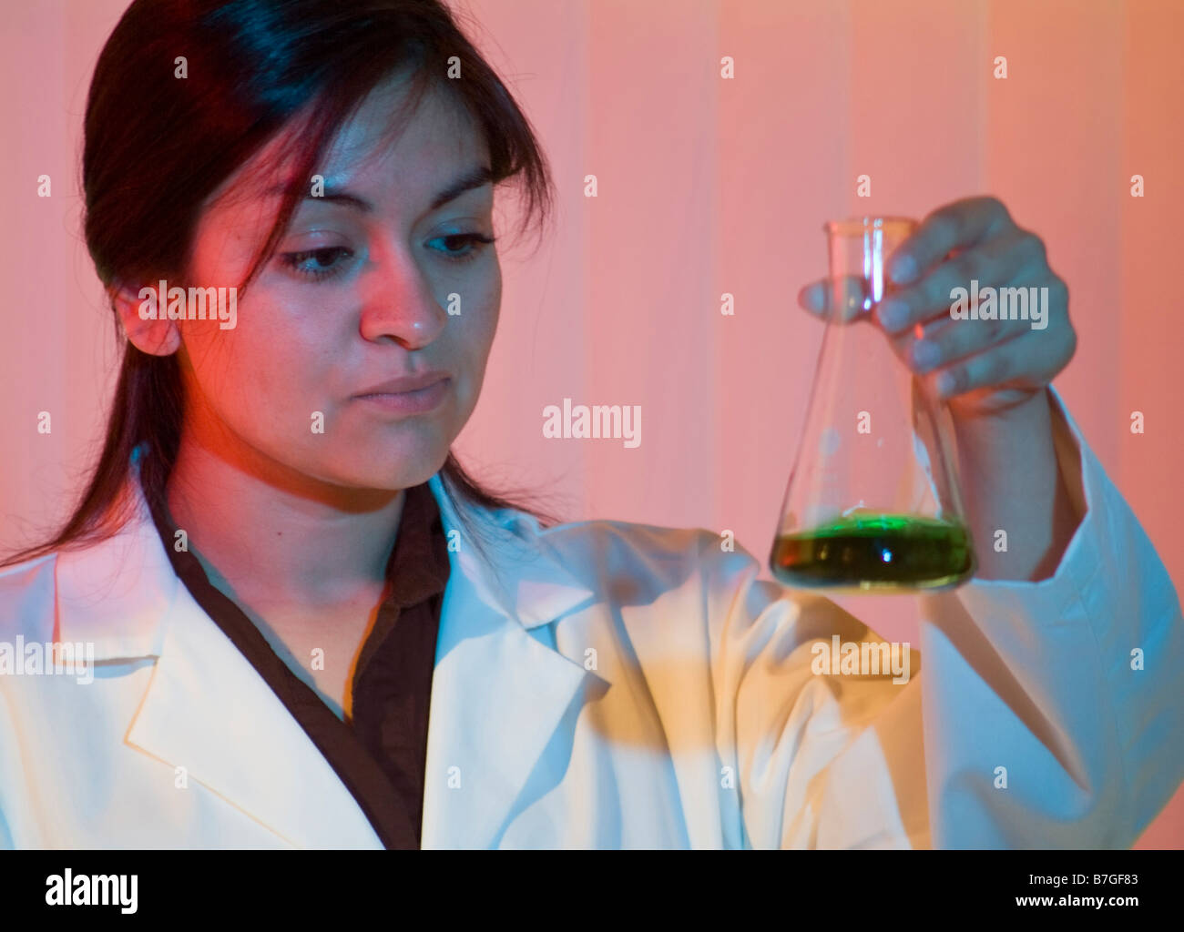 Eine junge Frau, gekleidet wie ein Blick auf den Inhalt von einem Glaskolben Techniker Stockfoto