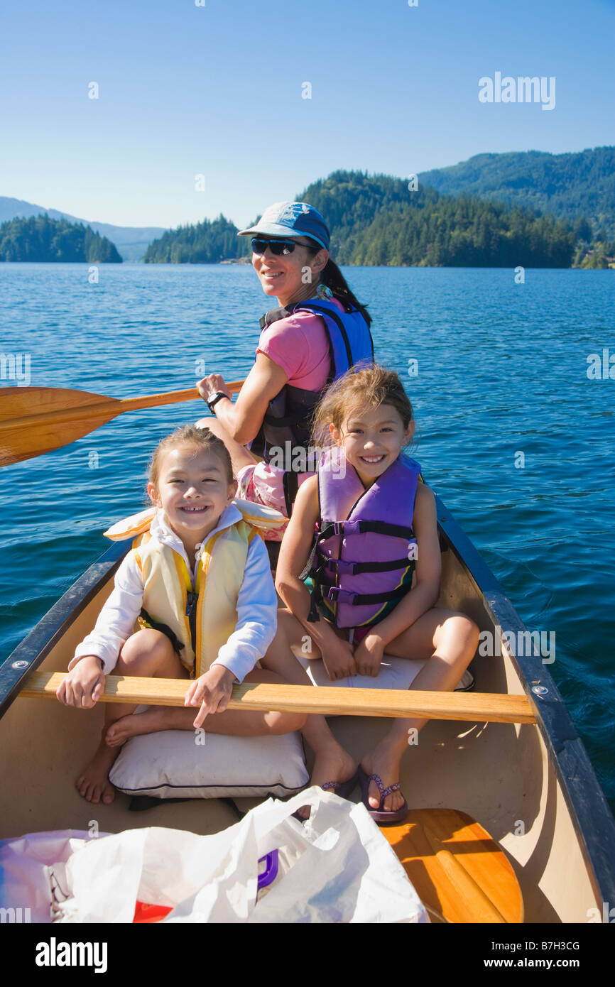 Mutter und Töchter Rudern Kanu auf See Stockfoto