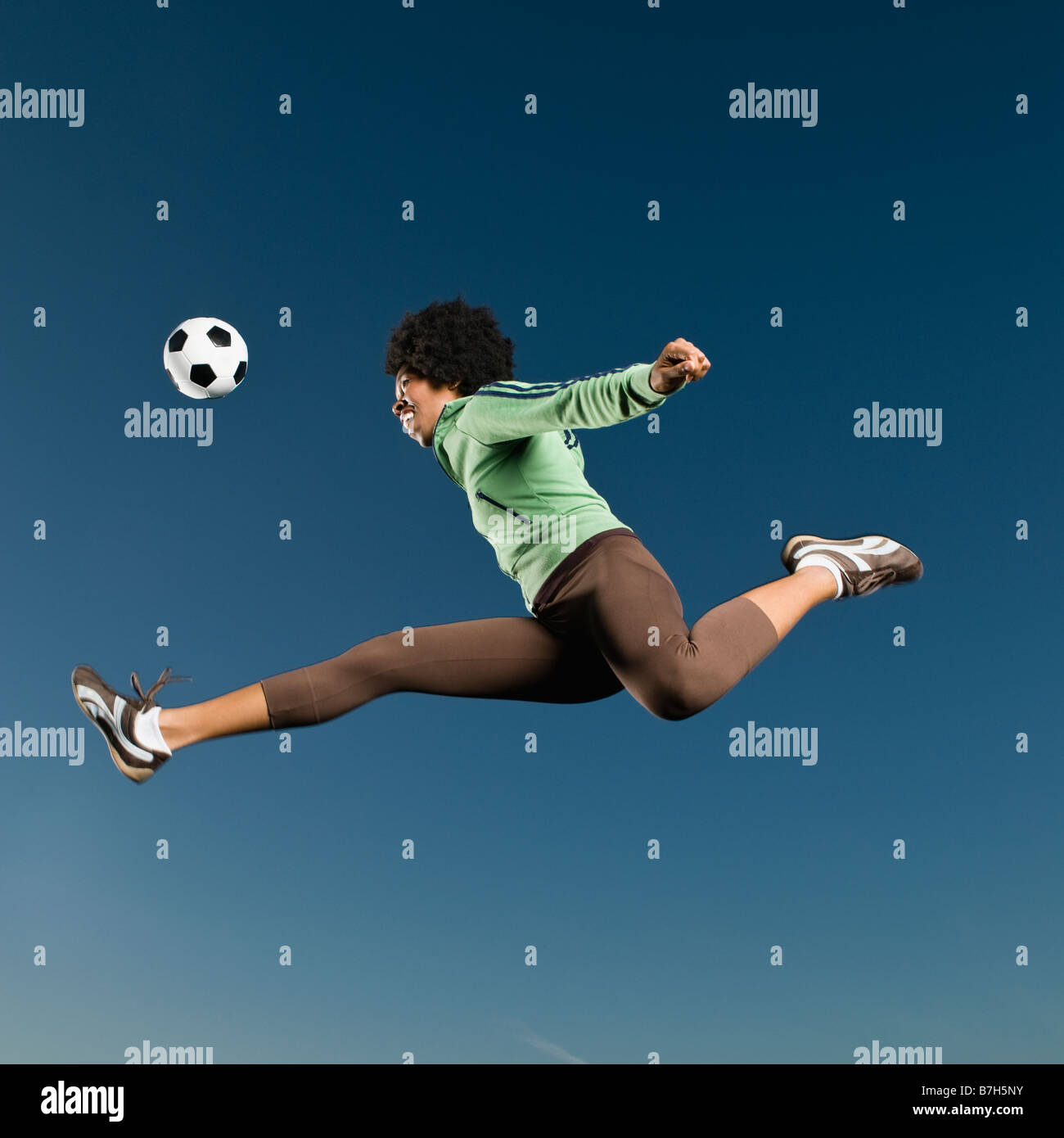 Afrikanerin, die Fußball spielen, in der Luft Stockfoto