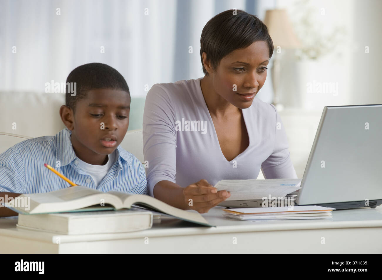 Afrikanischen jungen machen Hausaufgaben nächsten Mutter auf computer Stockfoto