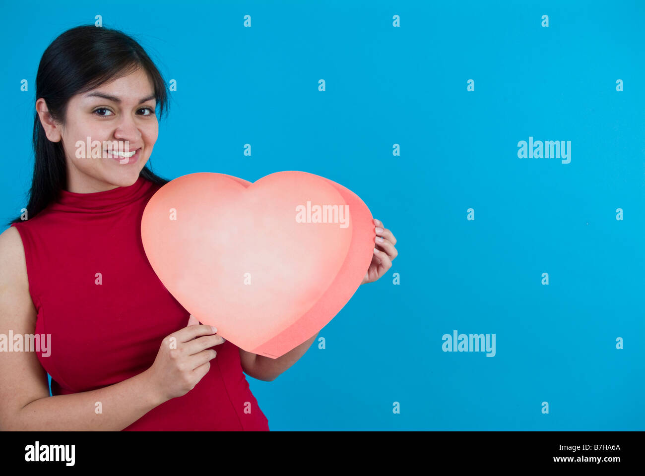 Eine hübsche junge Frau hält eine große Valentine genommen auf einem blauen Hintergrund mit Textfreiraum Stockfoto